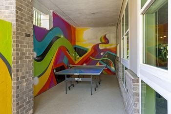 A room with a colorful mural on the wall and a ping pong table.